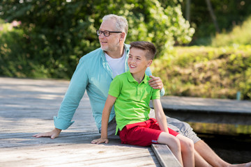 grandfather and grandson sitting on river berth