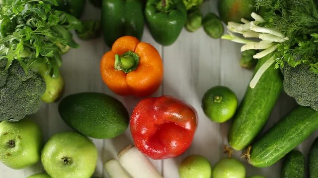 The woman puts the peppers on the table with green vegetables