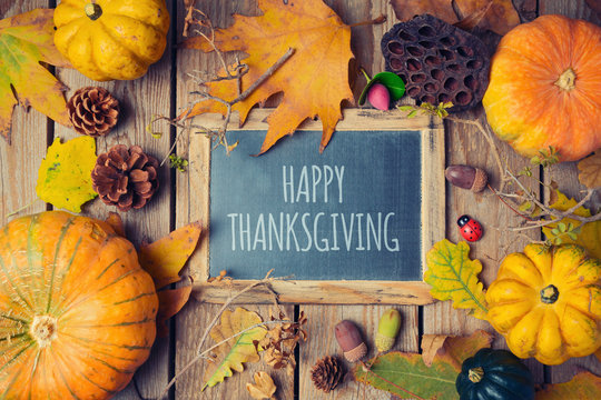 Thanksgiving background with chalkboard. Autumn pumpkin and fall leaves on wooden table. View from above