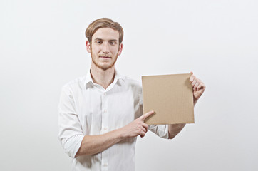 Young Adult Man in White Shirt Holding a Cardboard Inscription And Pointing at It