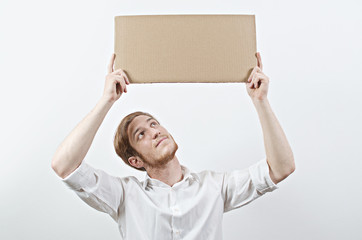 Young Adult Man in White Shirt Holding a Big Cardboard Inscription Above His Bent Head, Looking Up...