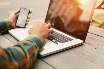 Young man typing on computer and sitting in street cafe, freelancer doing his job outdoors