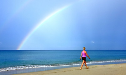 The tourist walk on the beach and rainbow.