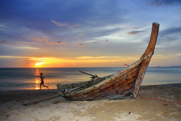 Boat on the beach at sunset and the jogging tourist.