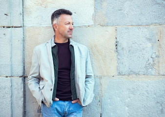 Obraz premium Handsome middle-aged man posing over old ancient street wall, Pa