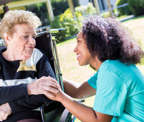 Afroamerican nurse comforting aged woman