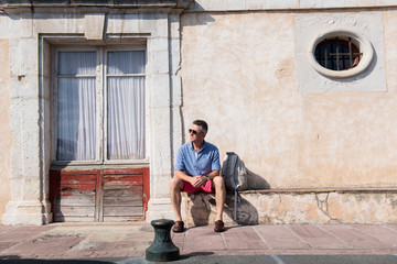 Fototapeta na wymiar Handsome man. Outdoor male portrait. Middle-aged man sitting nea