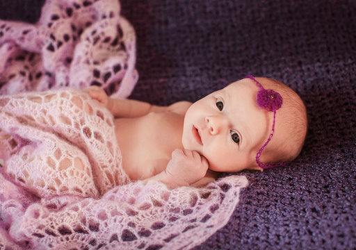 Newborn girl with little violet flower on her head