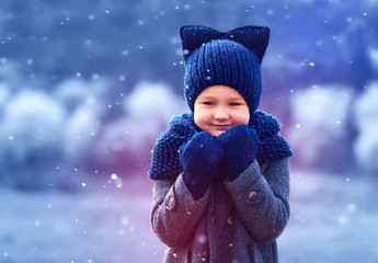 cute kid in knitted wear and felted coat under winter snow