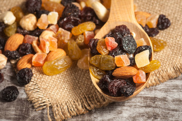 Nuts and dried fruits mix on a rustic sack and wooden background