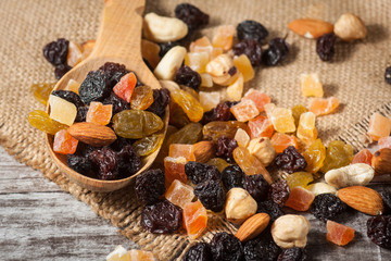 Nuts and dried fruits mix on a rustic sack and wooden background