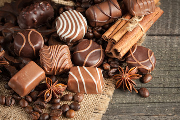 Assortment of dark, white and milk chocolate stack, chips. Chocolate and coffee beans on rustic wooden sacking background. Spices, cinnamon. Selective macro focus. Chocolates background. Sweets