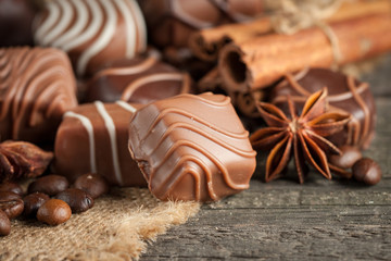 Assortment of dark, white and milk chocolate stack, chips. Chocolate and coffee beans on rustic wooden sacking background. Spices, cinnamon. Selective macro focus. Chocolates background. Sweets