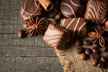 Assortment of dark, white and milk chocolate stack, chips. Chocolate and coffee beans on rustic wooden sacking background. Spices, cinnamon. Selective macro focus. Chocolates background. Sweets