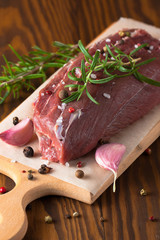 Close-up of raw fresh marble meat on board with condiments on white background. Chili pepper, rosemary, salt and black pepper. Ready for steak.