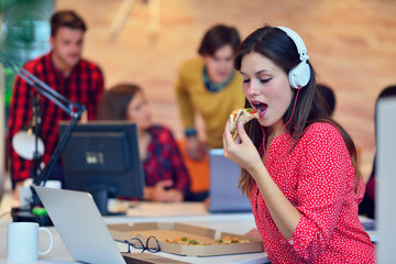Cheerful office girl enjoying pizza at lunchtime