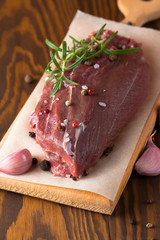 Close-up of raw fresh marble meat on board with condiments on white background. Chili pepper, rosemary, salt and black pepper. Ready for steak.