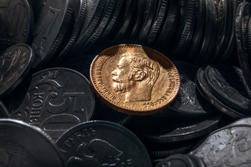 coin from precious metal of gold against the background of coins of small advantage from cheap metals.
