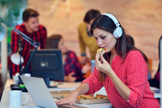 Cheerful office girl enjoying pizza at lunchtime