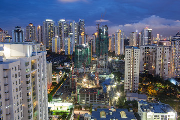 Naklejka premium Construction works in residential area of Kuala Lumpur with high-rise apartment blocks. City illuminated in the dusk, Malaysia