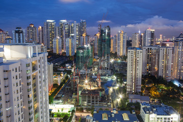 Construction works in residential area of Kuala Lumpur with high-rise apartment blocks. City illuminated in the dusk, Malaysia