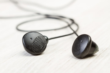 Cascos auriculares negros vista de cerca y de frente sobre un fondo de madera rústico