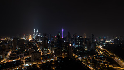 Fototapeta premium Kuala Lumpur view, Malaysia. Night city lights and transport traffic on illuminated highways. Panoramic view with Petronas Twin Towers and Menara KL Tower