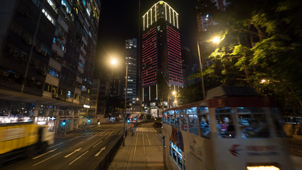 Hong Kong at night. View to the street with high-ride buildings, road transport and double-decker tramway
