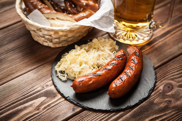 Pretzels, bratwurst and sauerkraut on wooden table