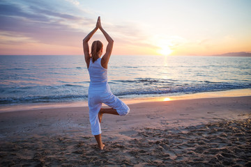 Fototapeta na wymiar Caucasian woman practicing yoga at seashore