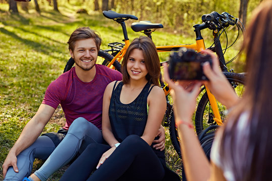 A woman taking pictures of sporty couple after bicycle ride