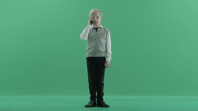 schoolboy is talking on the phone on green screen background