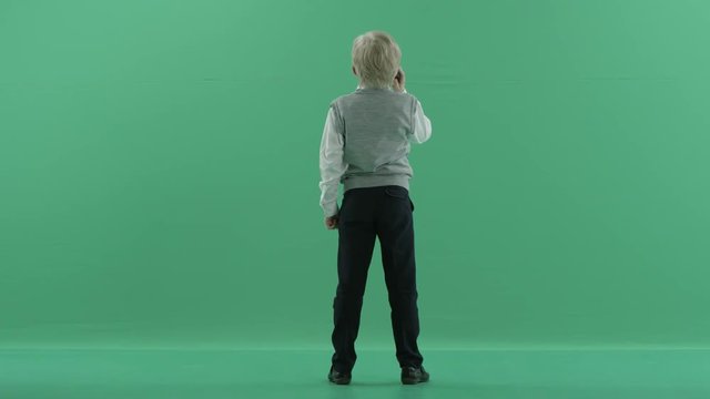 schoolboy is talking on the phone on green screen background