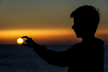 Silhouette of a teenager boy on sunset