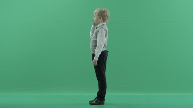 schoolboy is talking on the phone on green screen background