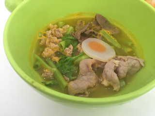 horizontal photo of noodles on green bowl with pork and vegetables