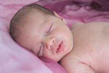 newborn sleeping in a pink background