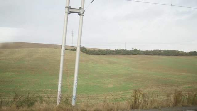 View from train - High voltage pylons at wheat meadows at sunne day