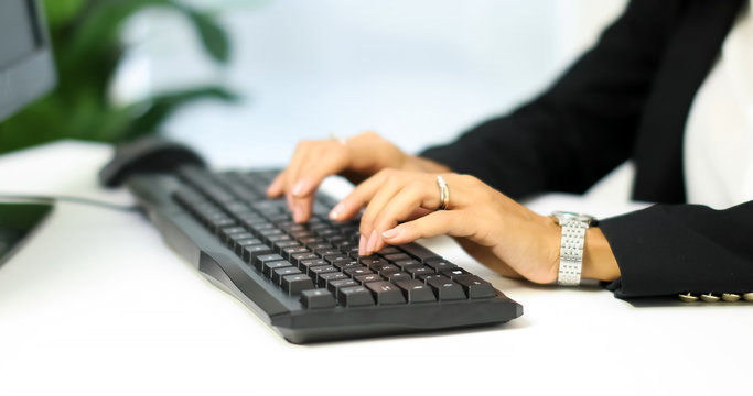 Young smiling businesswoman writing on pc