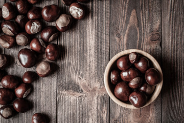 Pile of horse chestnuts on a bamboo bowl on wooden table - vintage