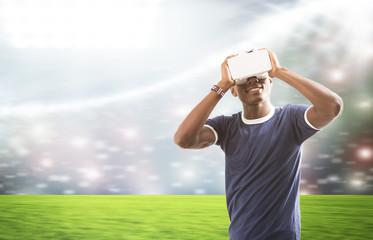 Young man with virtual reality headset or 3d glasses over football field on stadium background