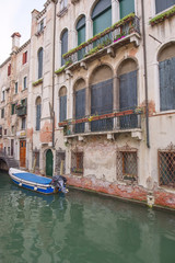 Fototapeta na wymiar Narrow canal among old colorful brick houses and boat in Venice, Italy.