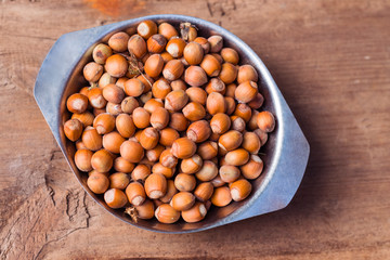 Hazelnuts in the bowl on old vintage wooden background