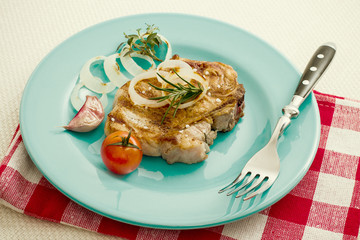 Juicy grilled pork chop with onion rings