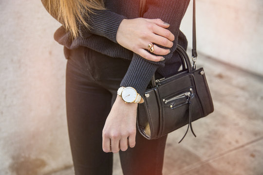 close up fashion details, young business woman holding her bag. wearing golden jewelry, and watch.

