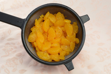 Rinsed canned Mandarin Orange slices in strainer draining in bowl