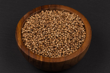 Coriander seeds in  small wooden bowl