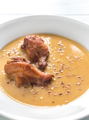 Portion of pea cream soup with smoked chicken wings