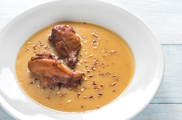 Portion of pea cream soup with smoked chicken wings