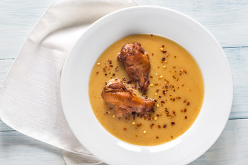 Portion of pea cream soup with smoked chicken wings